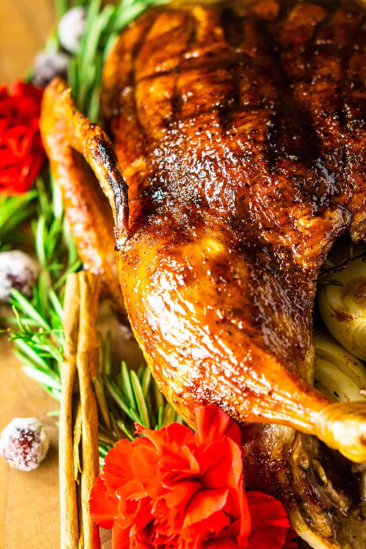 The Christmas roast duck with holiday decor around it on a cutting board.