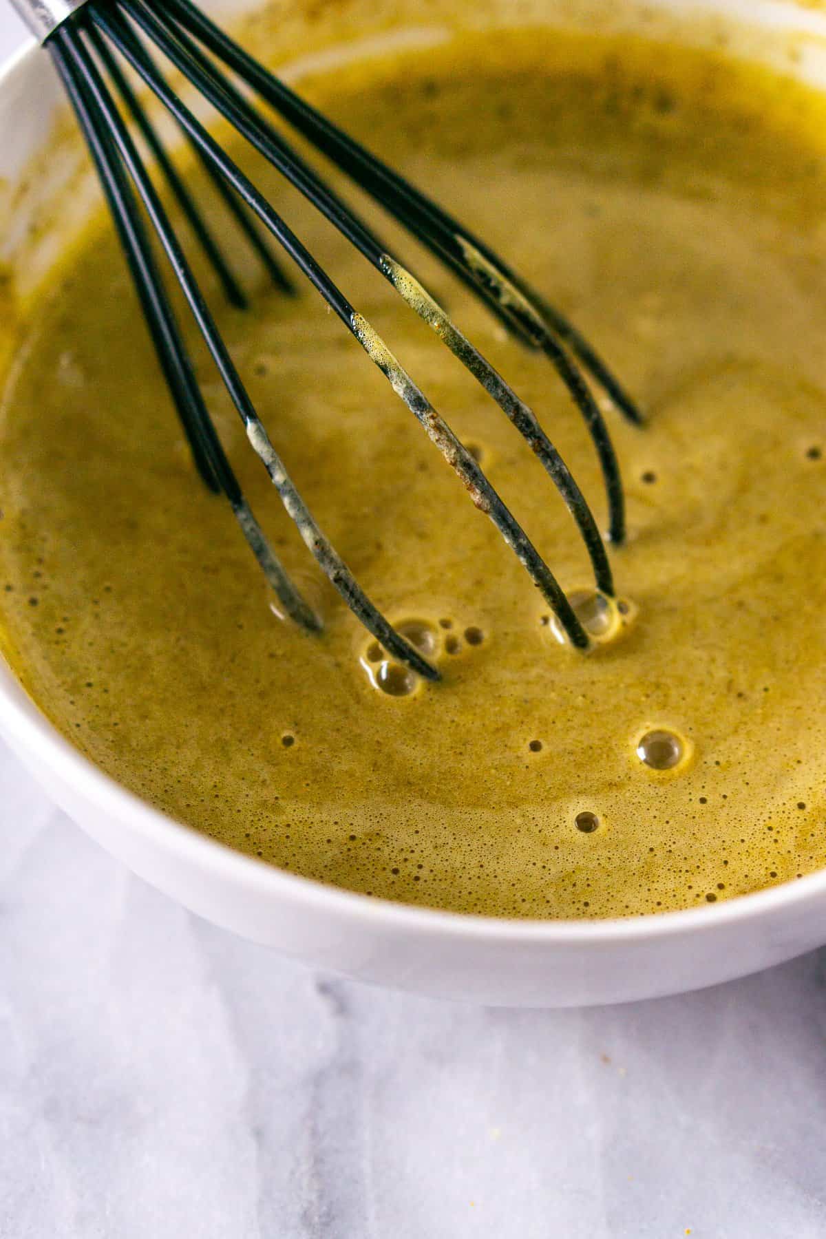 Tempering the cream mixture into the egg yolks after simmer with a whisk.