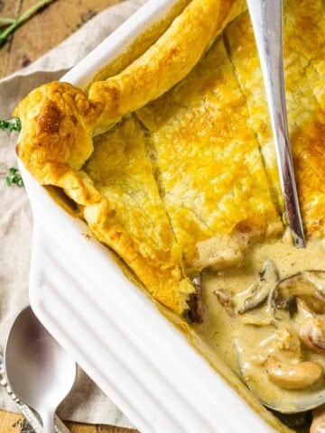The chicken and mushroom pie with a stainless steel spoon scooping into the dish to show the creamy filling.