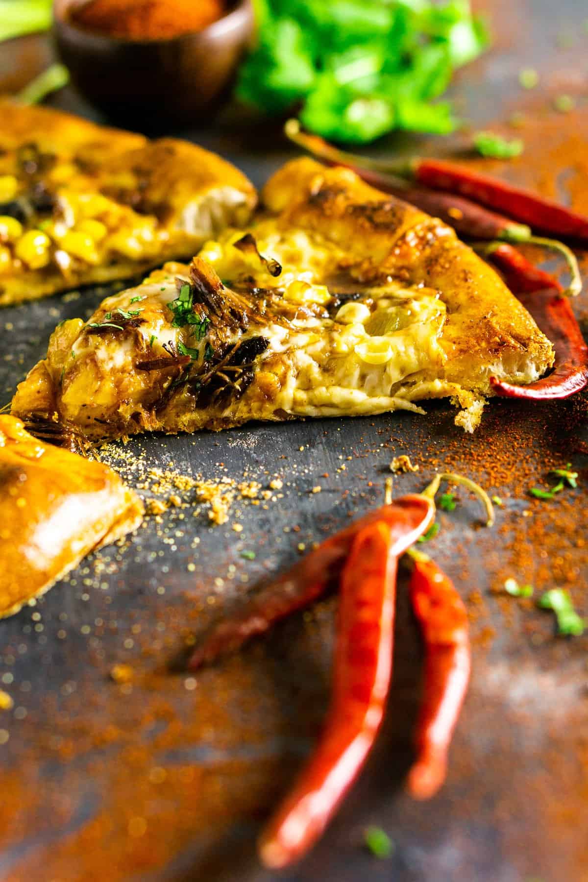 A closeup the pizza cut into slices with peppers in front of it.