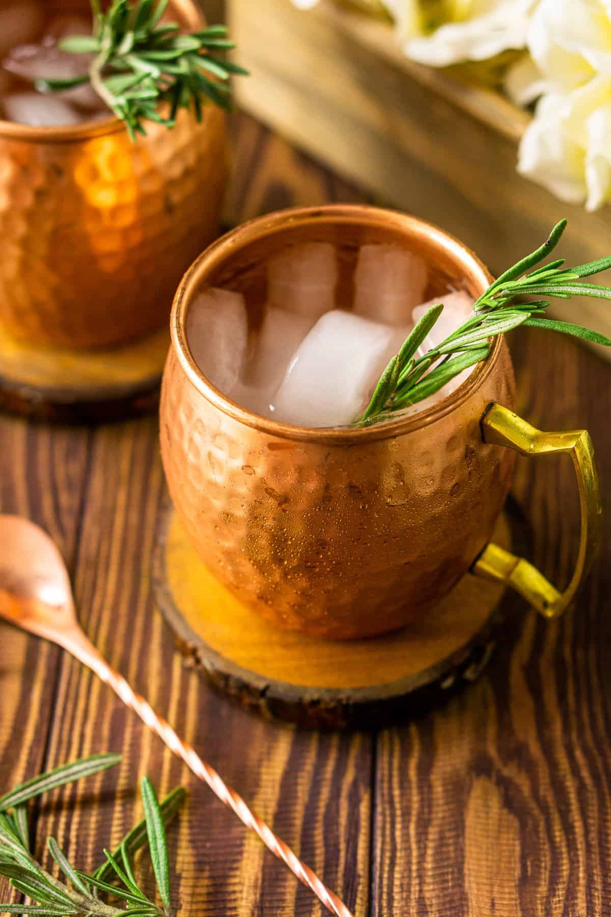 Looking down into a mule with the copper bar spoon and a rosemary sprig to the side.