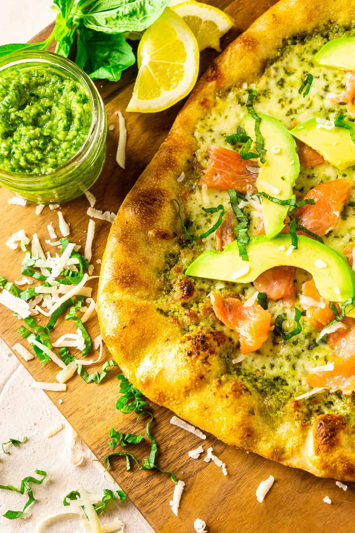 An aerial view of the smoked salmon and avocado pizza on the wooden cutting board.