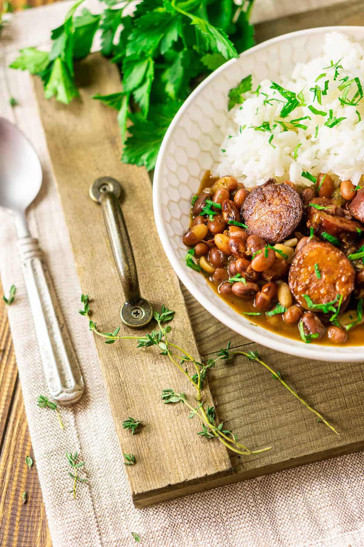 The Instant Pot red beans and rice on a wooden tray with fresh herbs around it.