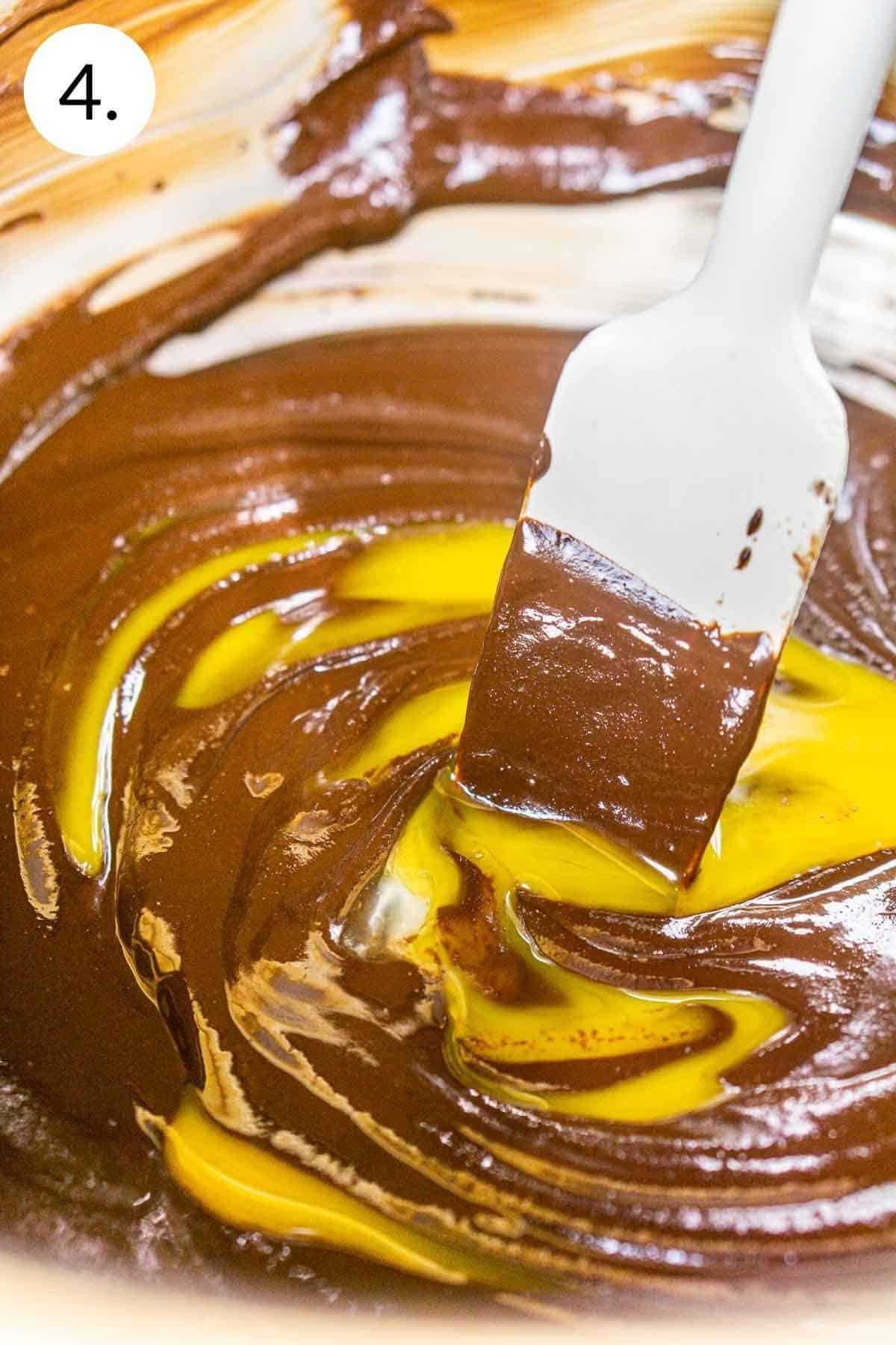 Stirring in the egg yolk into the melted chocolate so that it incorporates smoothly.