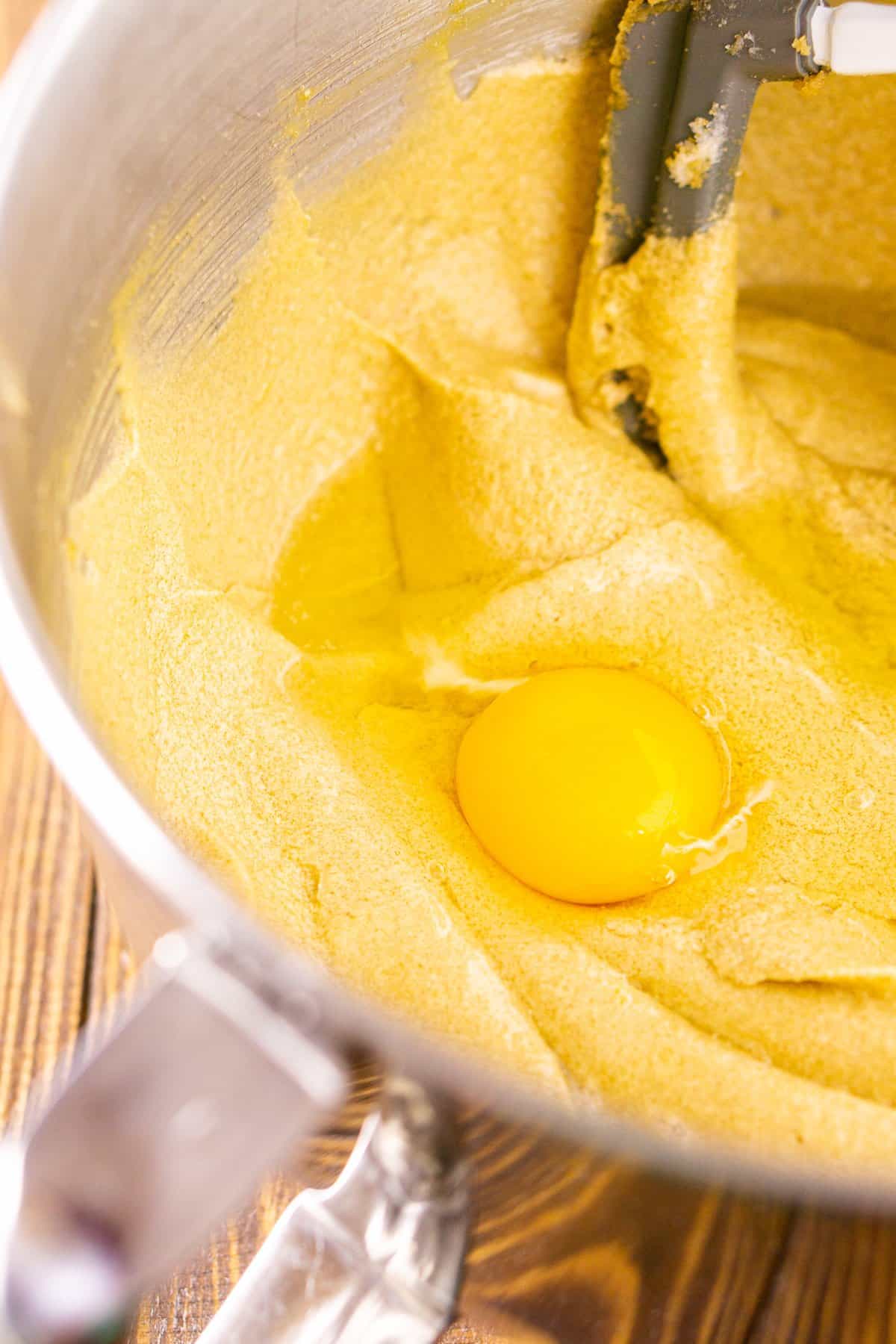 Adding the eggs to the batter one at a time in a mixing bowl.