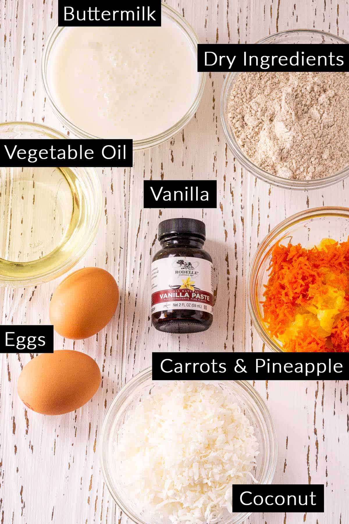 The carrot cake muffin ingredients on a white wooden board with black and white labels.