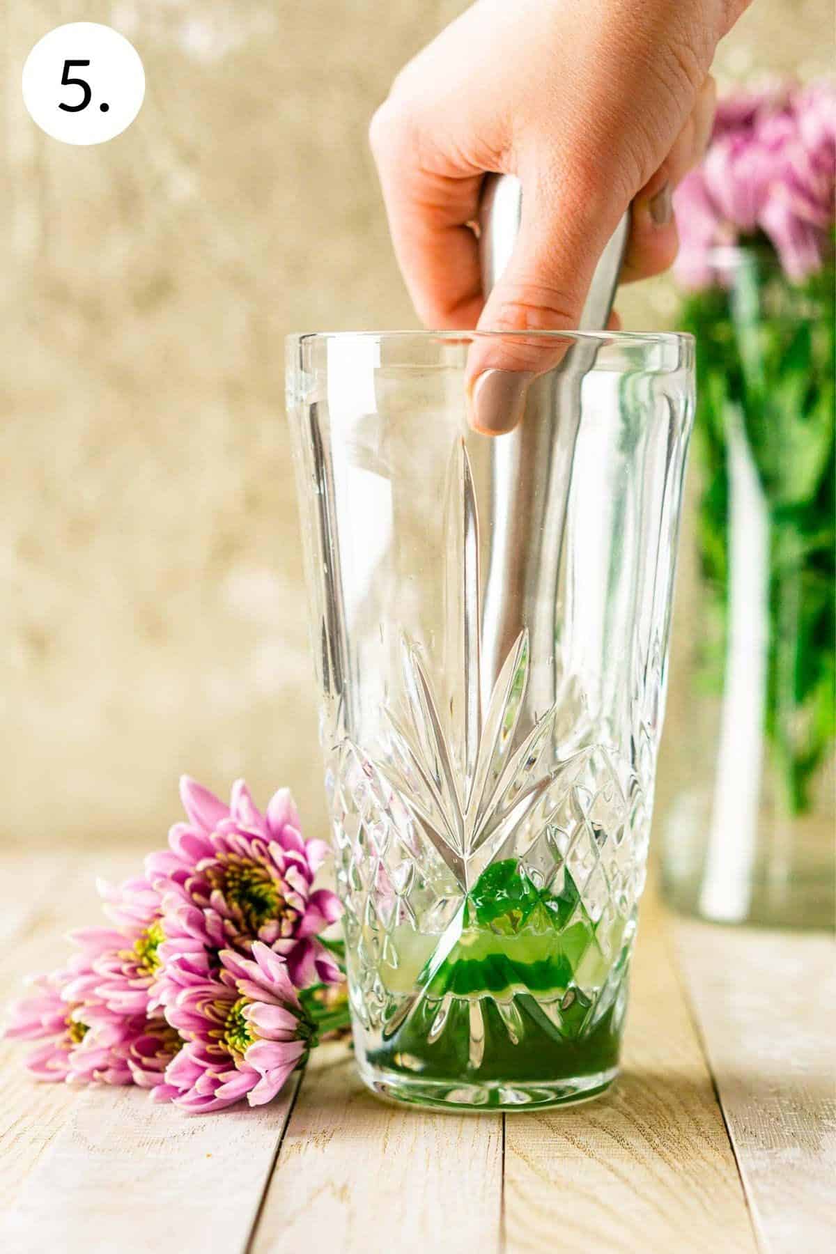 Muddling the jalapeno slices in a crystal cocktail shaker. 