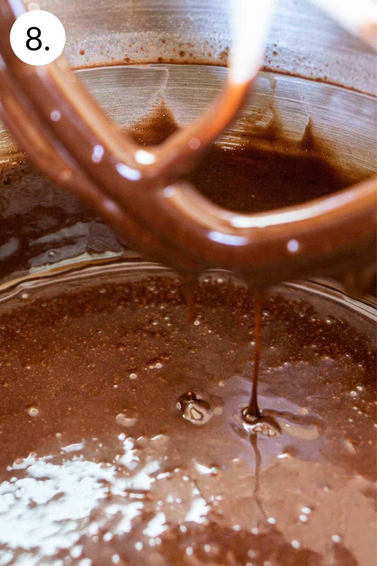 The thin batter drizzling off the beater into the mixing bowl.