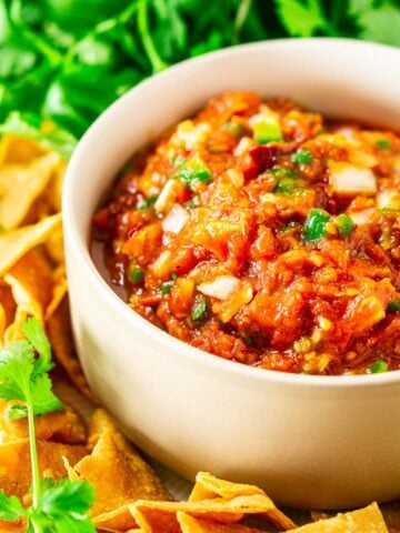 The tomato-chipotle salsa in a bowl with chips and cilantro surrounding it.