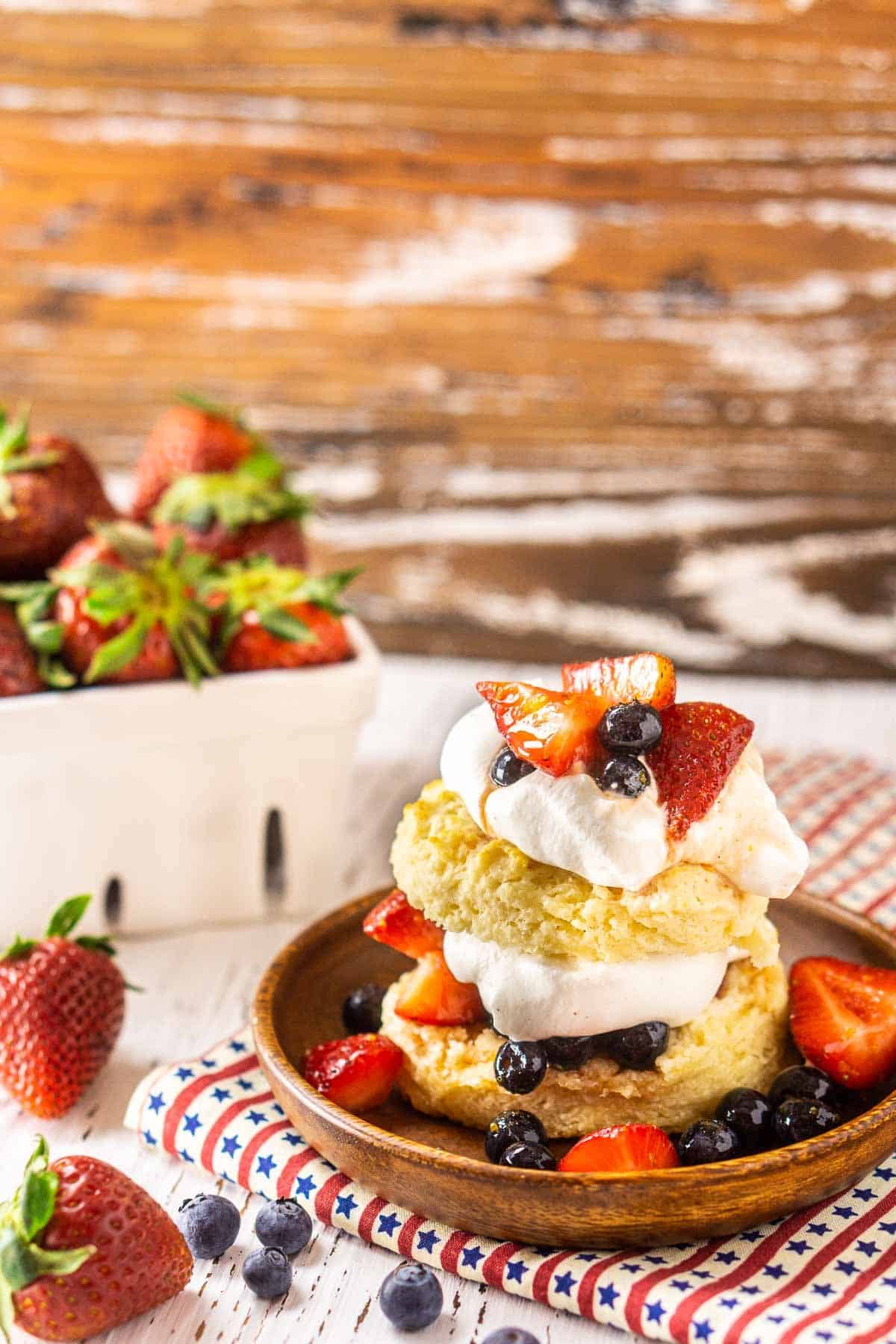A blueberry-strawberry shortcake with strawberries behind it and blueberries to the side.