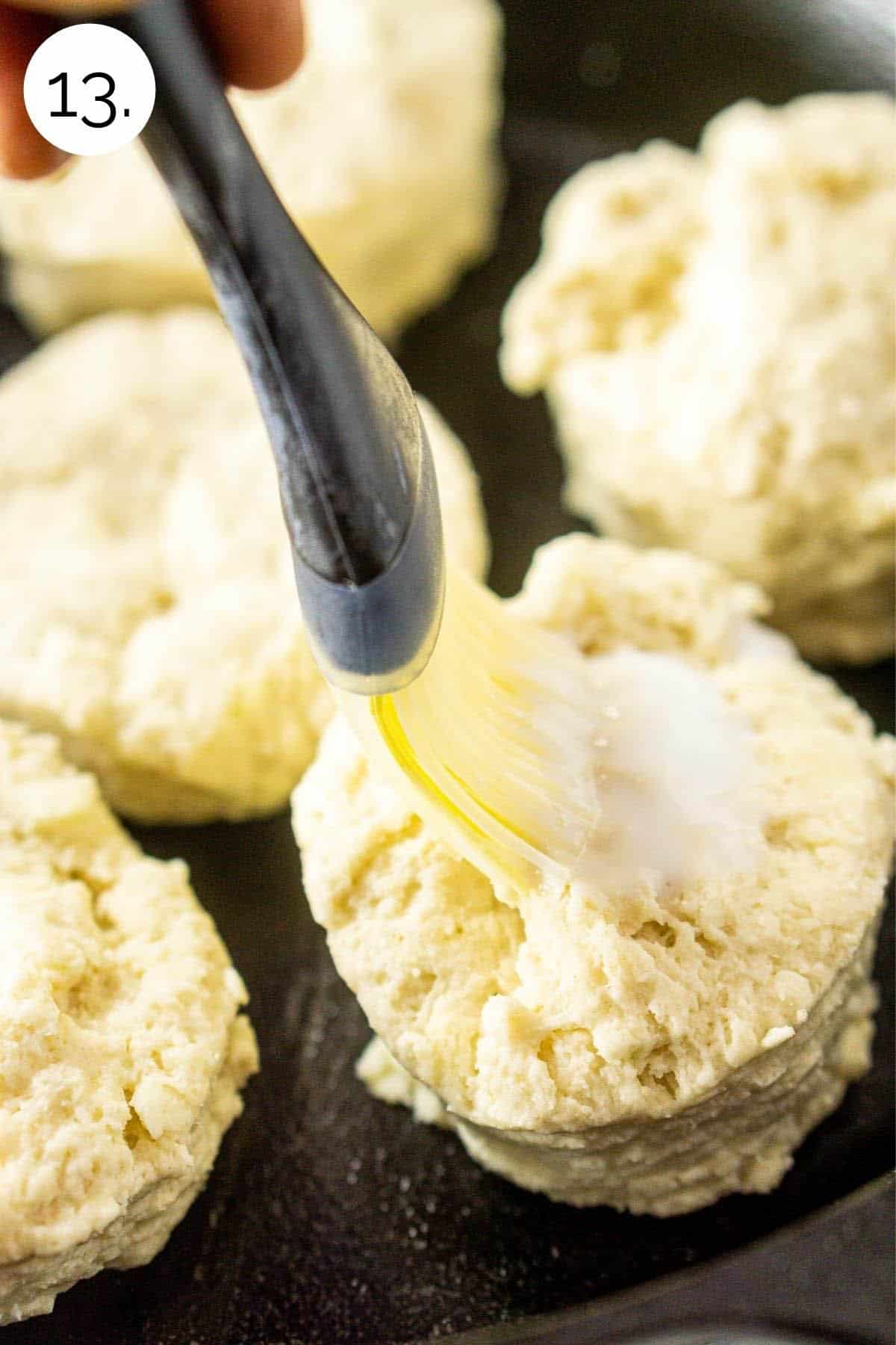 Brushing the shortcakes with buttermilk in a cast-iron skillet.