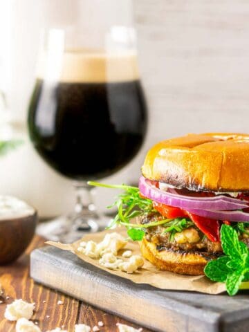 A minted lamb burger with a beer and greenery in the background.