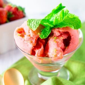 A close-up of the strawberry mojito sorbet on a green napkin with gold spoons.