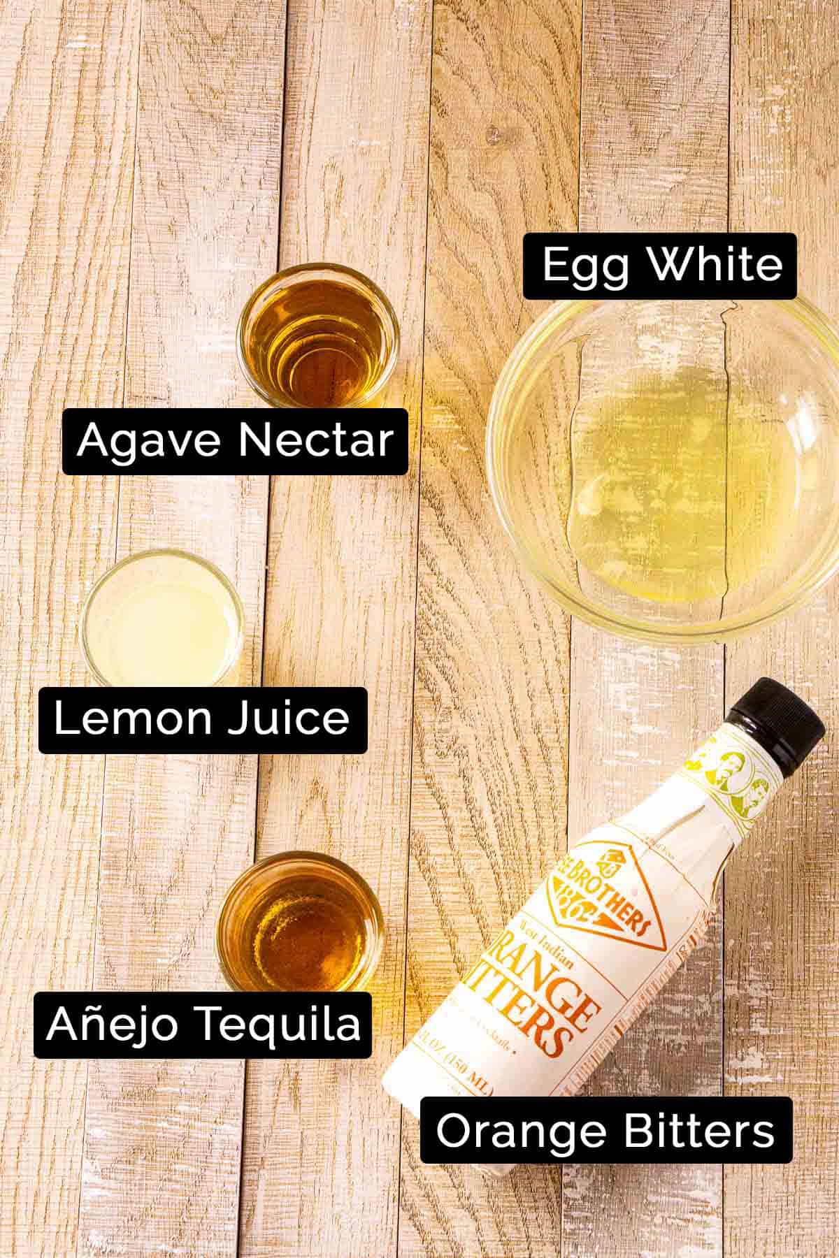 The tequila sour ingredients with black and white labels on a wooden board.