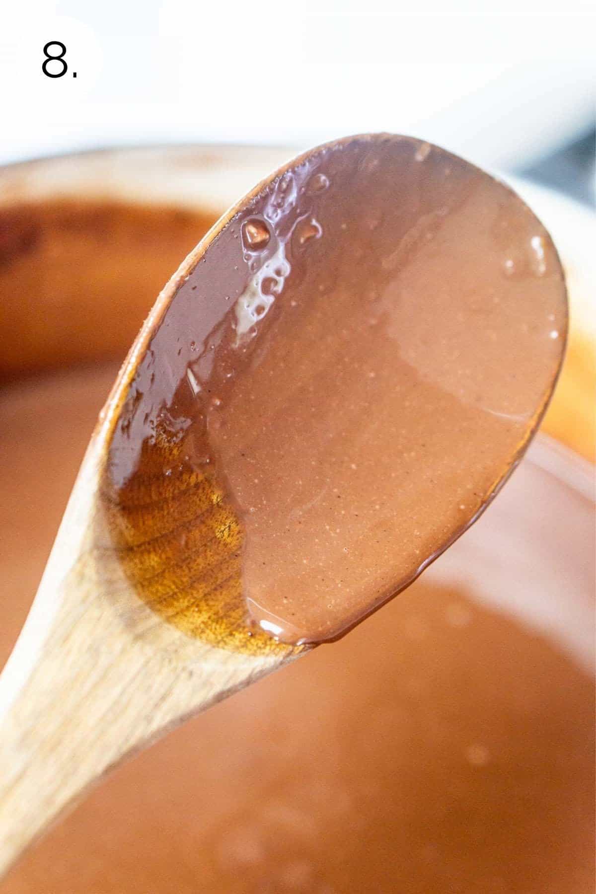 The ice cream mixture covering a wooden spoon after thickening.