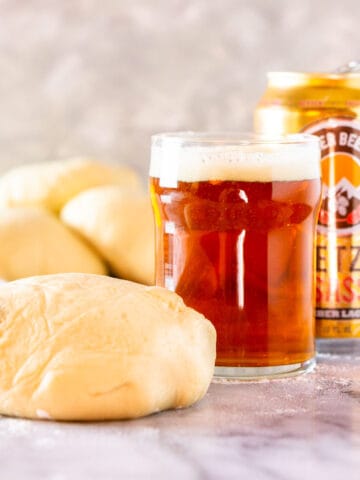 A glass and can of beer with make-ahead beer pizza dough balls.