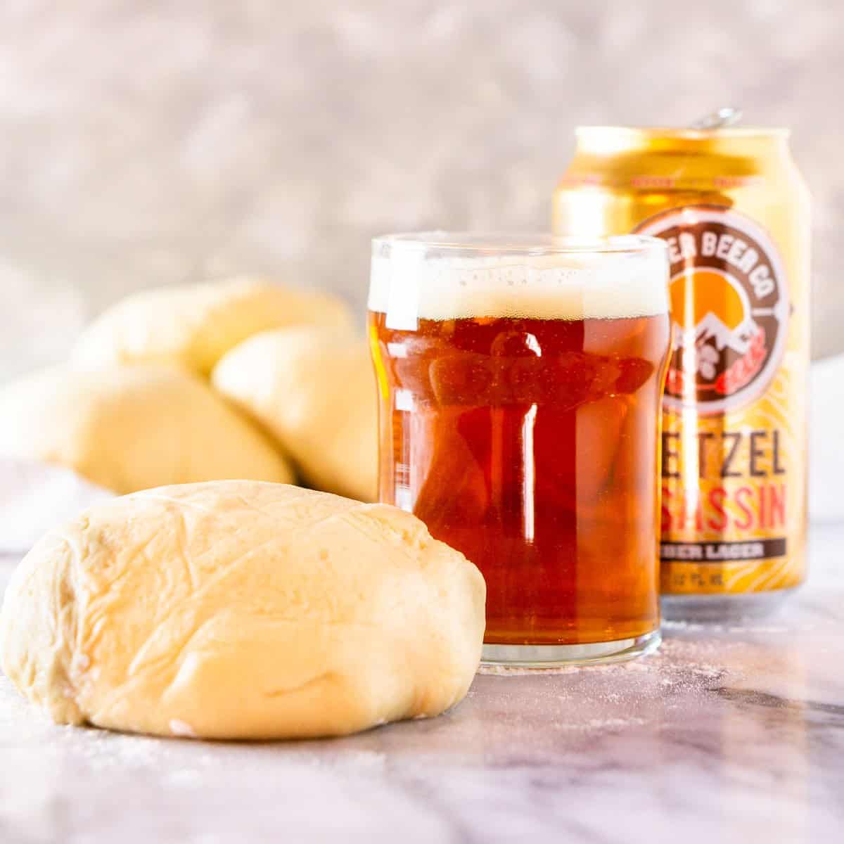 A glass and can of beer with make-ahead beer pizza dough balls.