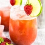 A roasted strawberry margarita on a white wooden board with a pink napkin to the side.