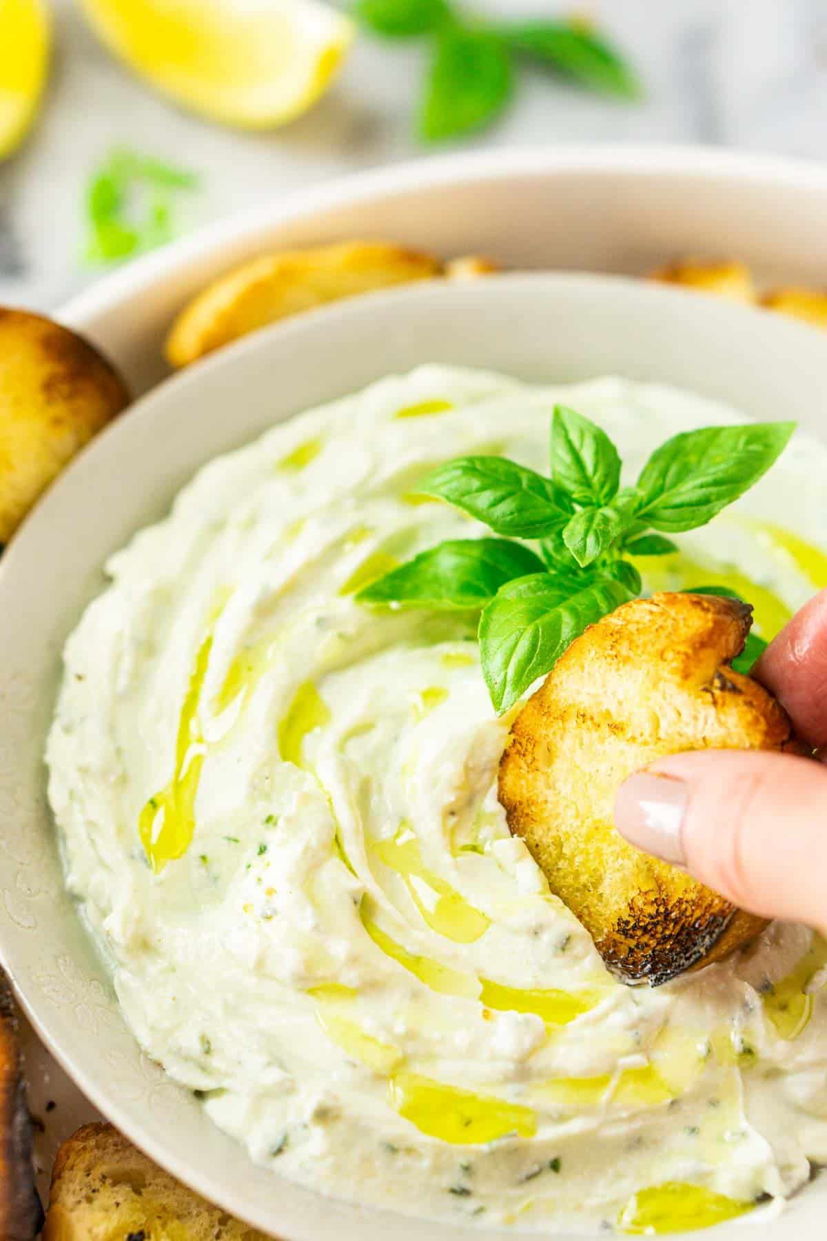 Dipping the grilled bread into the bowl of whipped ricotta.