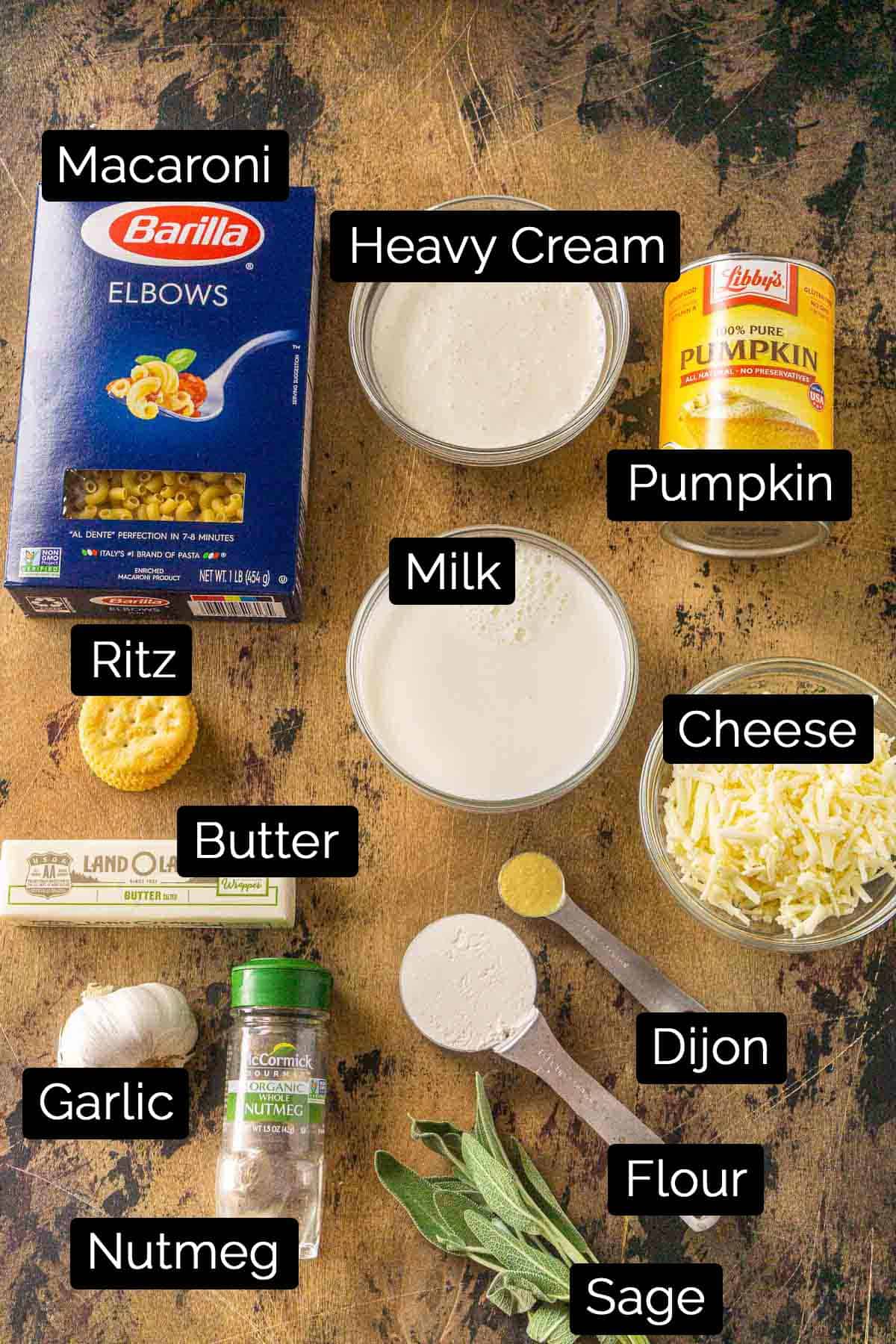 The pumpkin mac and cheese ingredients with labels on a wooden board.