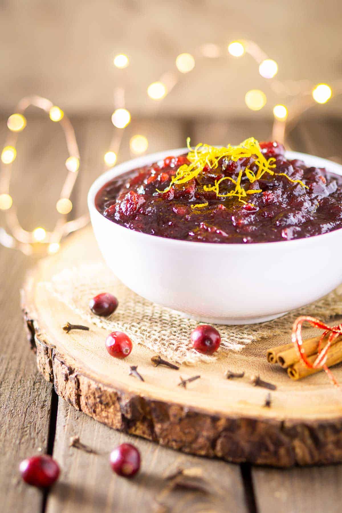 The brandy cranberry sauce in a white bowl with twinkle lights in the background.