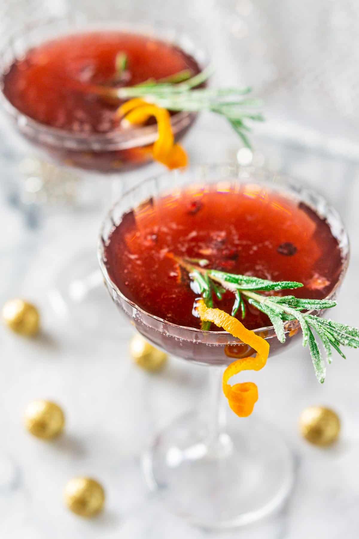 Two Christmas martinis with glittery decor around them.