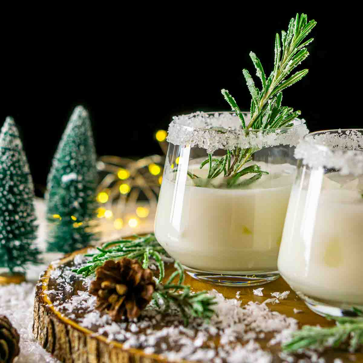 A festive Christmas cocktail on a wooden platter with fake snow around it.