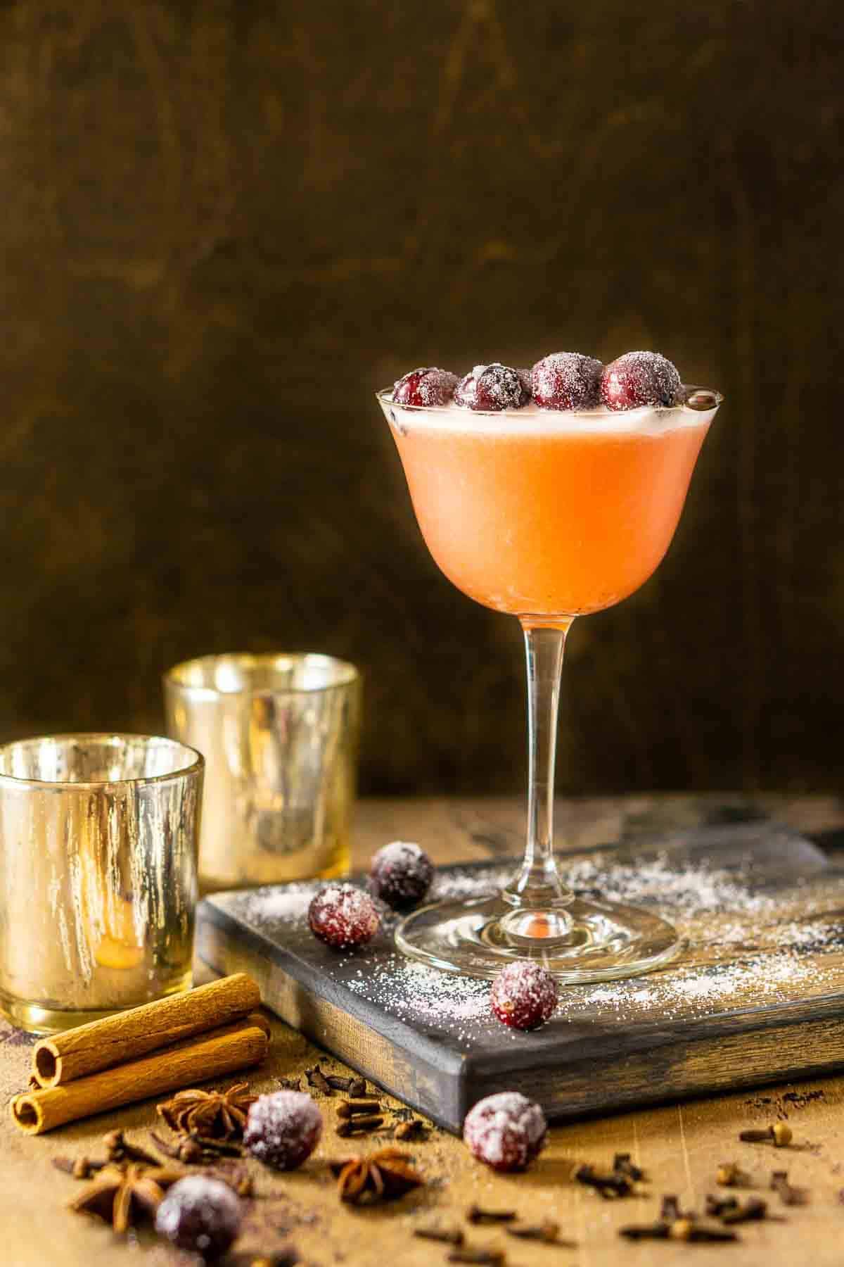 The cranberry bourbon sour with sugared cranberries and decor around it.