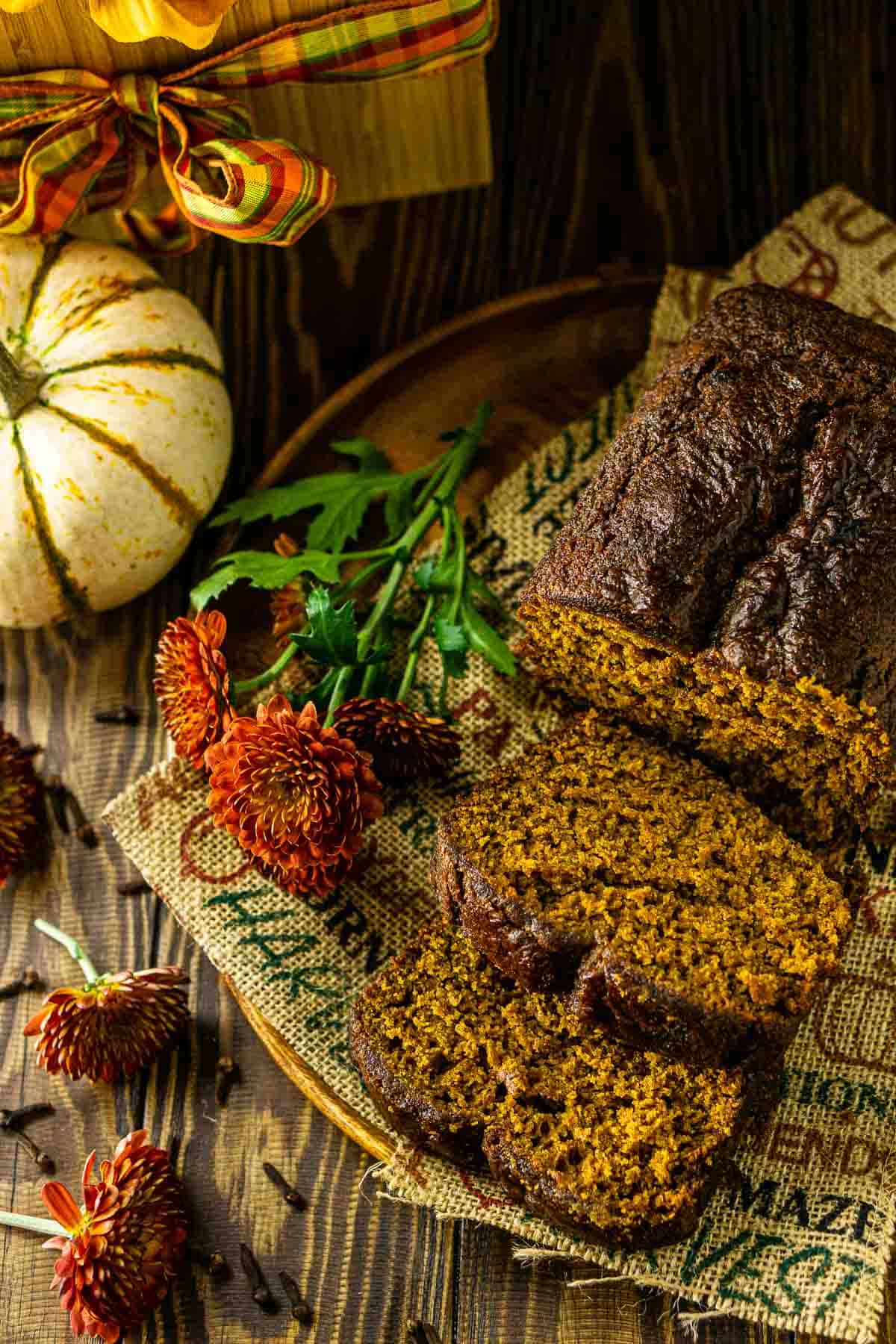 The pumpkin gingerbread loaf cut into slices with fall decor around it.