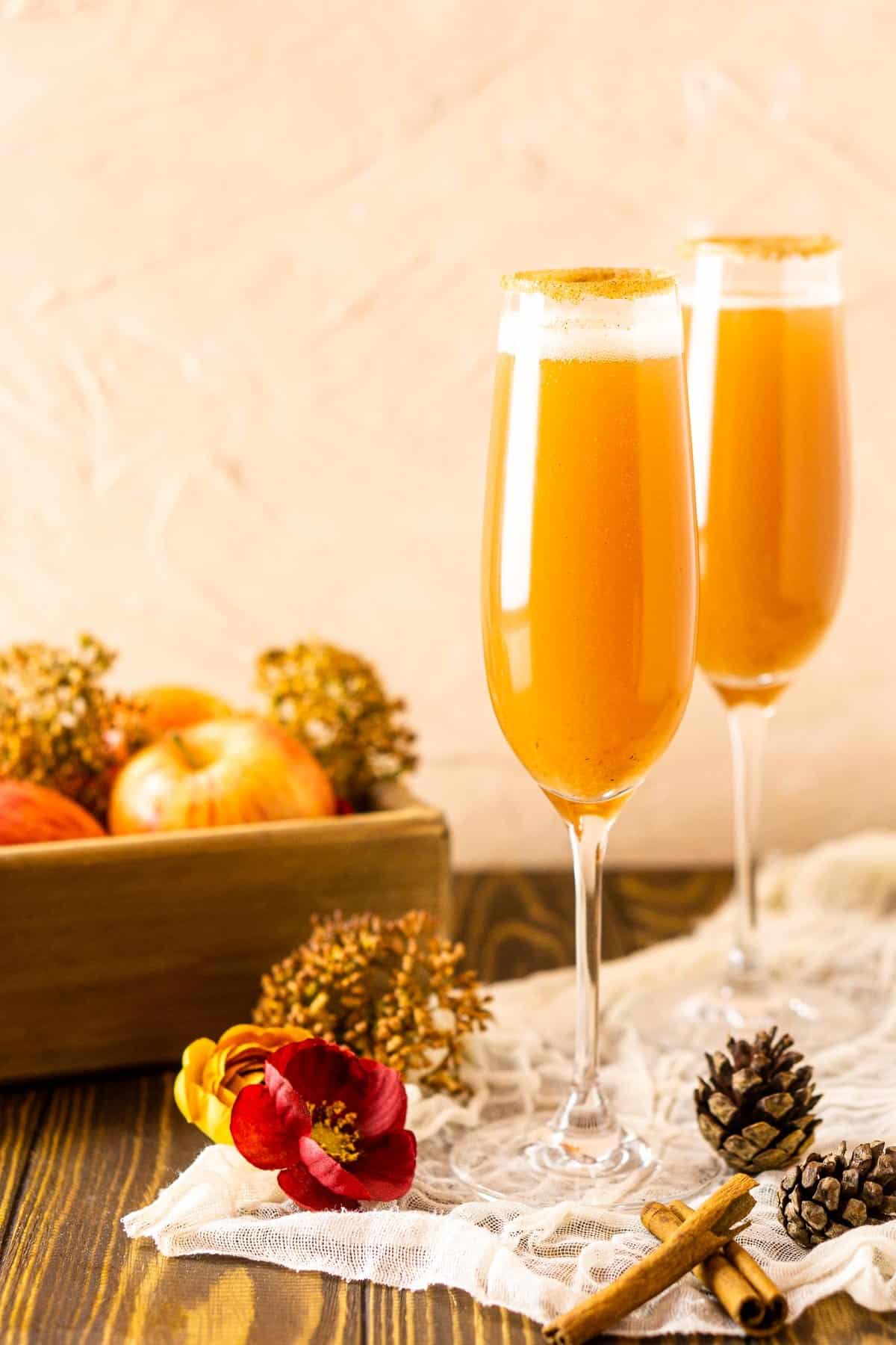 Two apple bellini Thanksgiving cocktails with fall decor to the side.