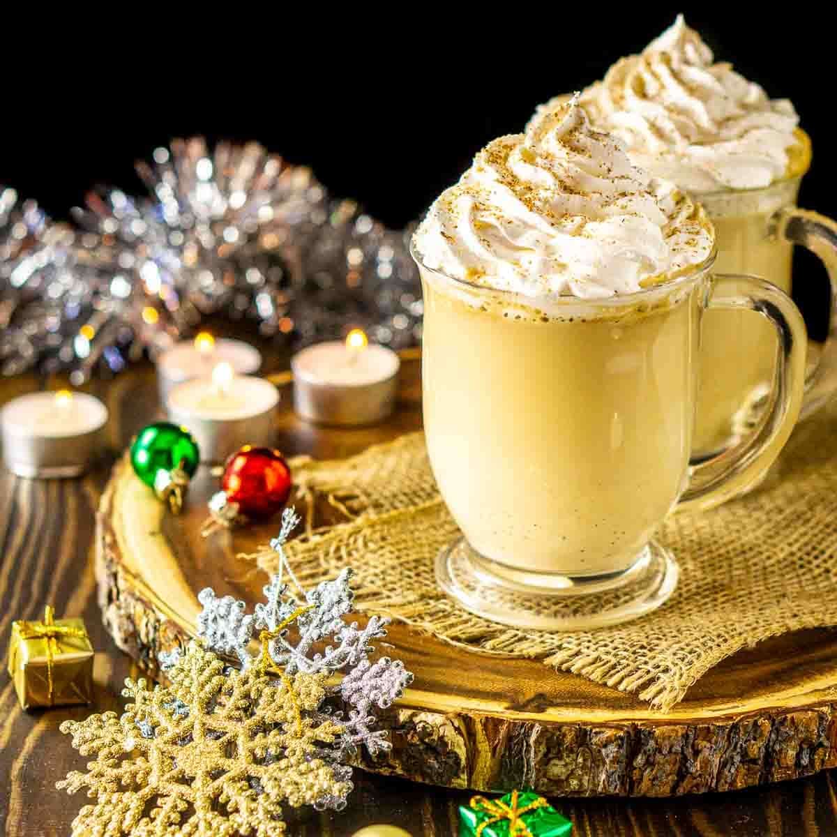 An eggnog latte on a wooden serving platter with Christmas decor around it.