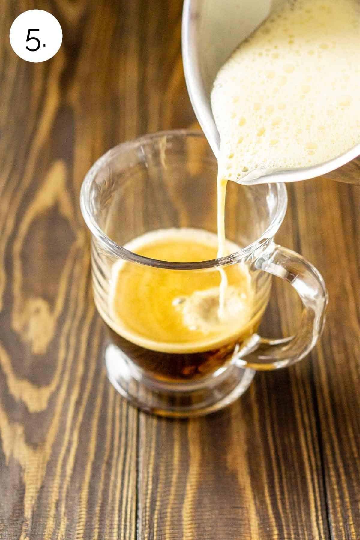 Pouring the frothed eggnog into a latte cup with espresso.