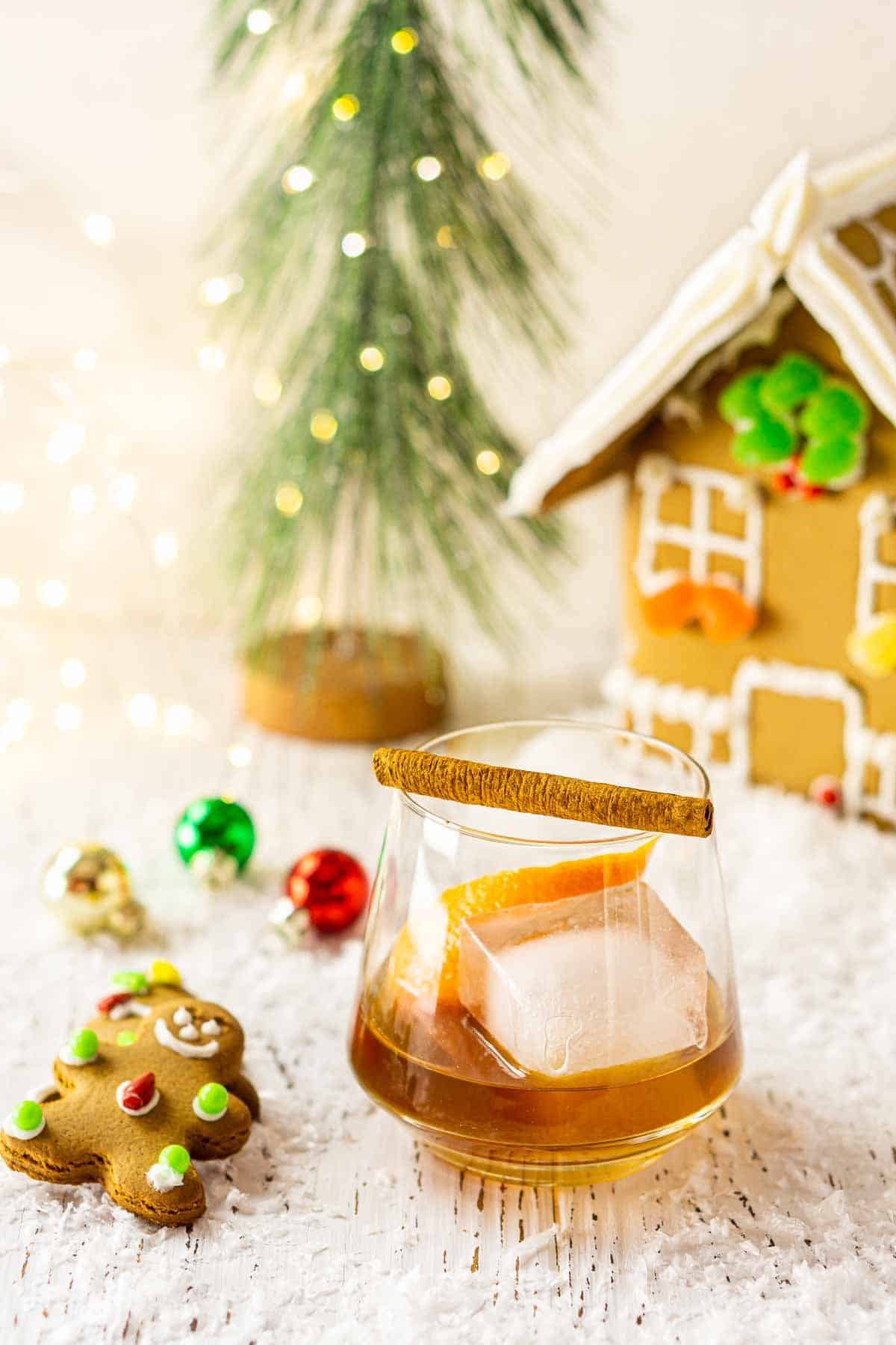 A gingerbread old fashioned with cookies and decor next to it.