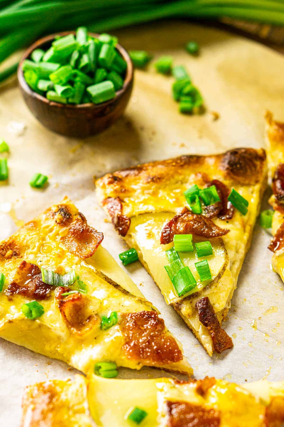 The baked potato pizza cut into slices on parchment paper.