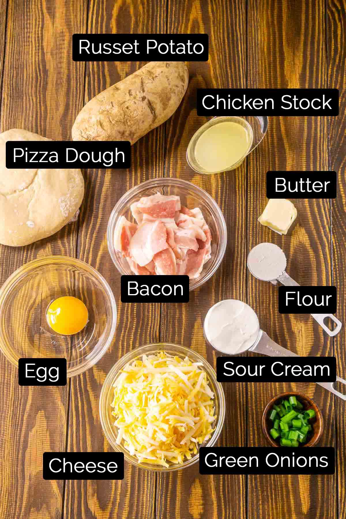 The baked potato pizza ingredients with labels on a wooden board.