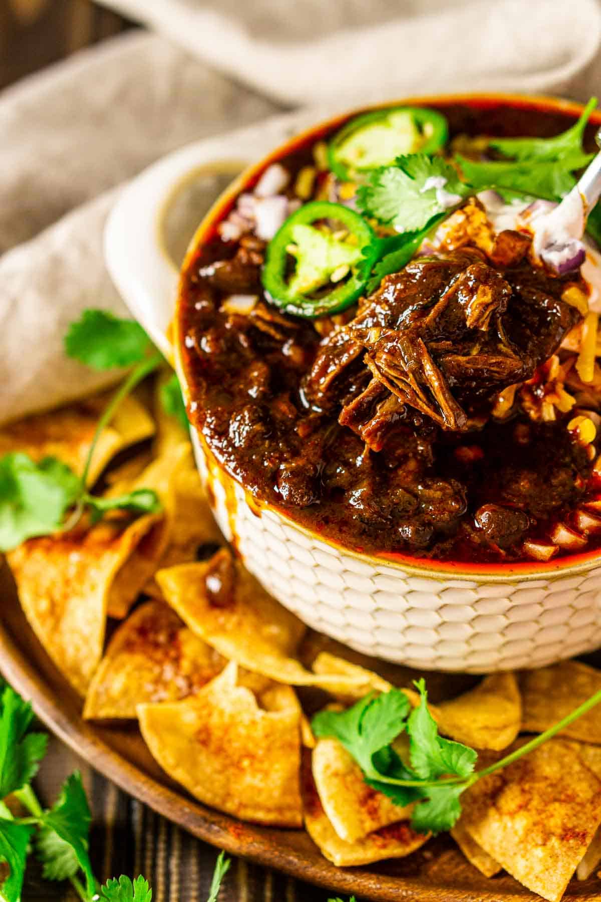 A spoonful of the short rib chili with chips and a napkin to the side.