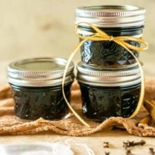 The brown sugar-chai simple syrup in small jars stacked on top of each other with a tea bag in front of them.