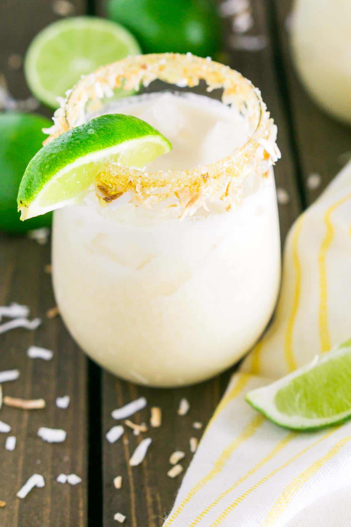 A coconut margarita on a yellow and white napkin with toasted coconut all around it.