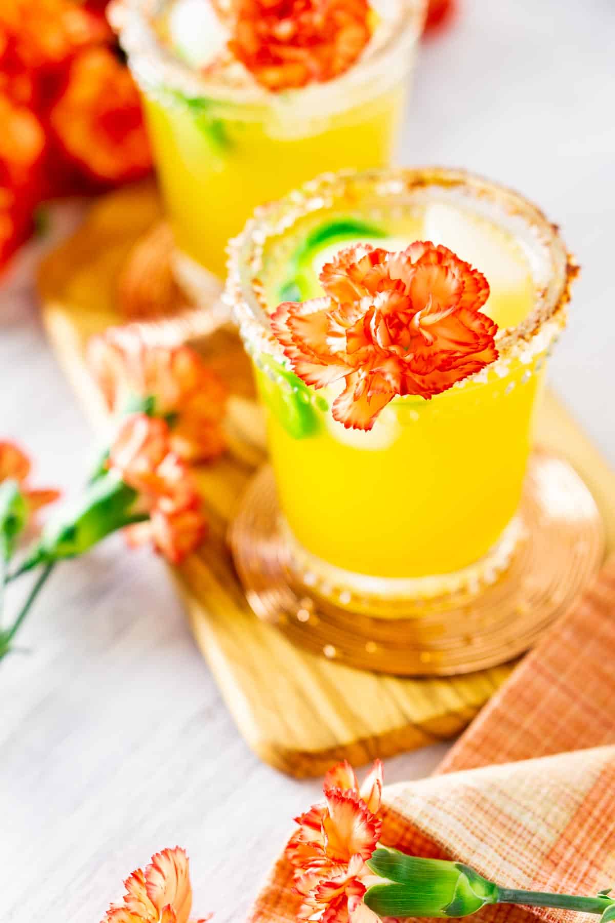 A jalapeno-mango margarita on a peach-colored napkin with colorful flowers.