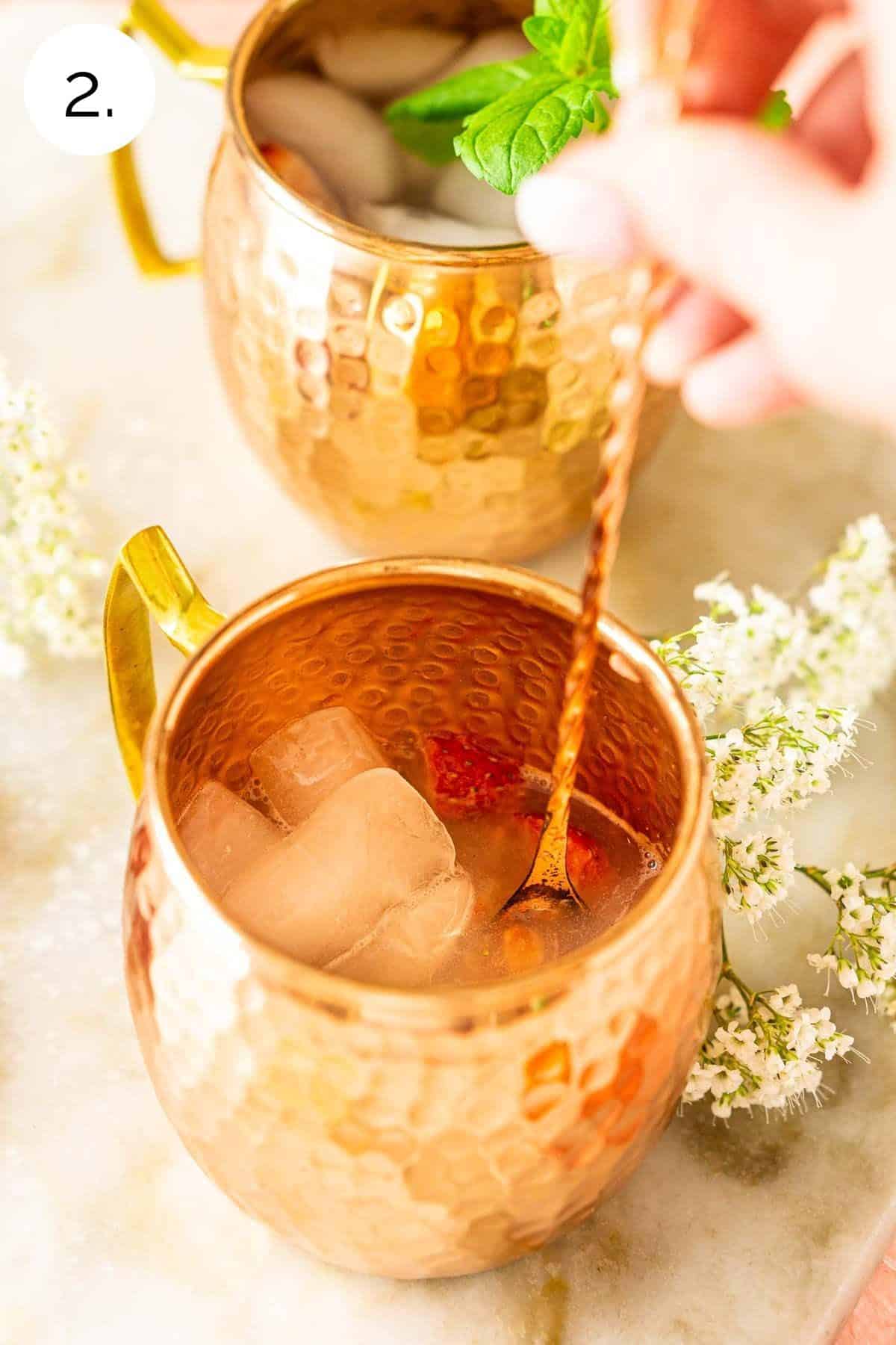 Stirring the ice and vodka in a copper mug to combine and chill the mixture.