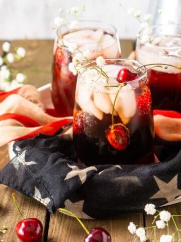An aerial view of three cherry vodka cocktails on flag-themed cloth.