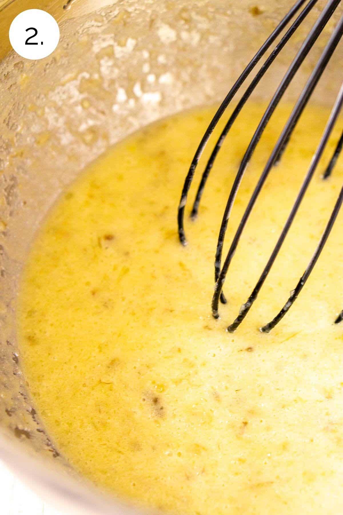 Whisking the wet ingredients together in a large stainless steel mixing bowl.