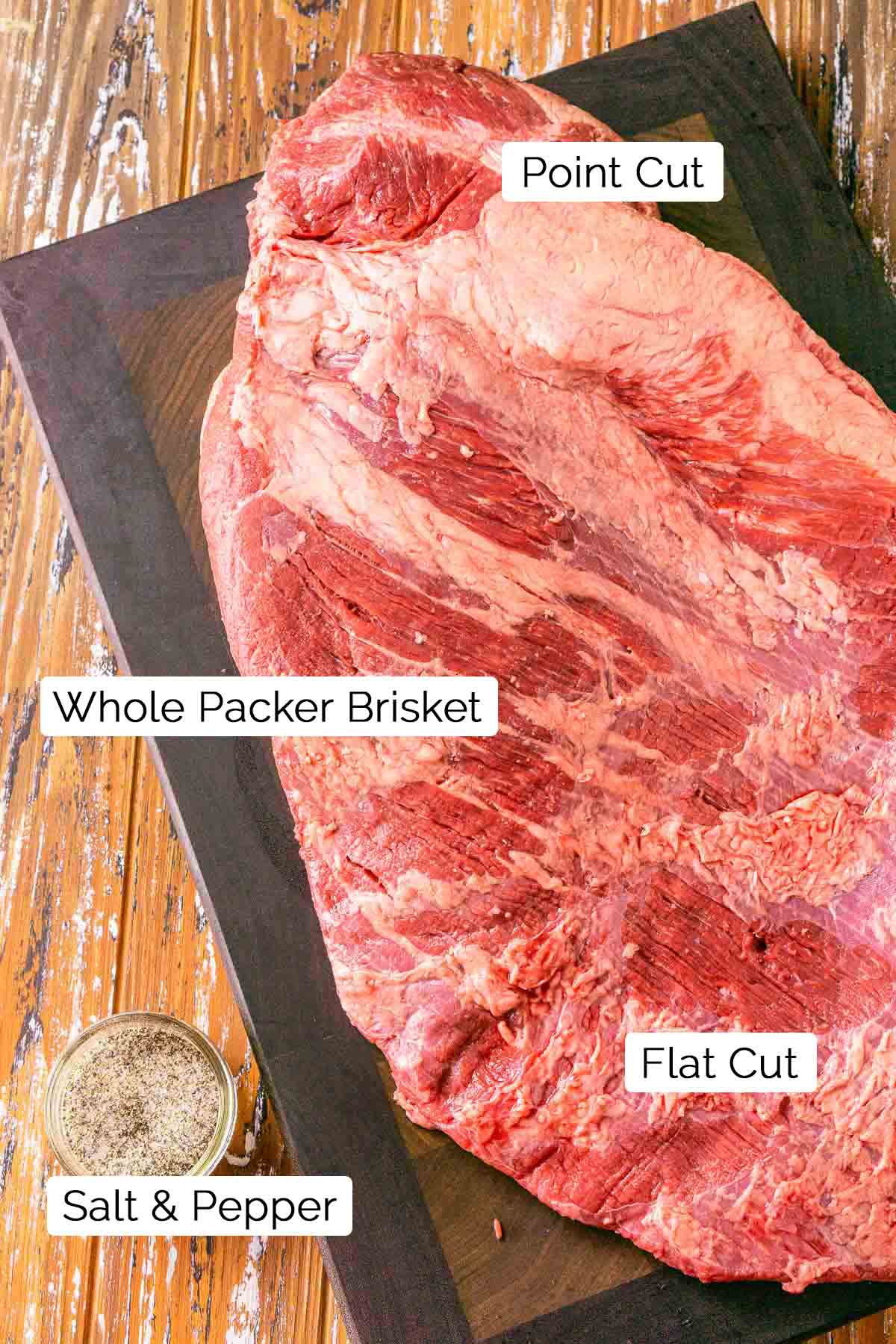 The whole packer brisket on a cutting board with the point and flat cuts labeled.