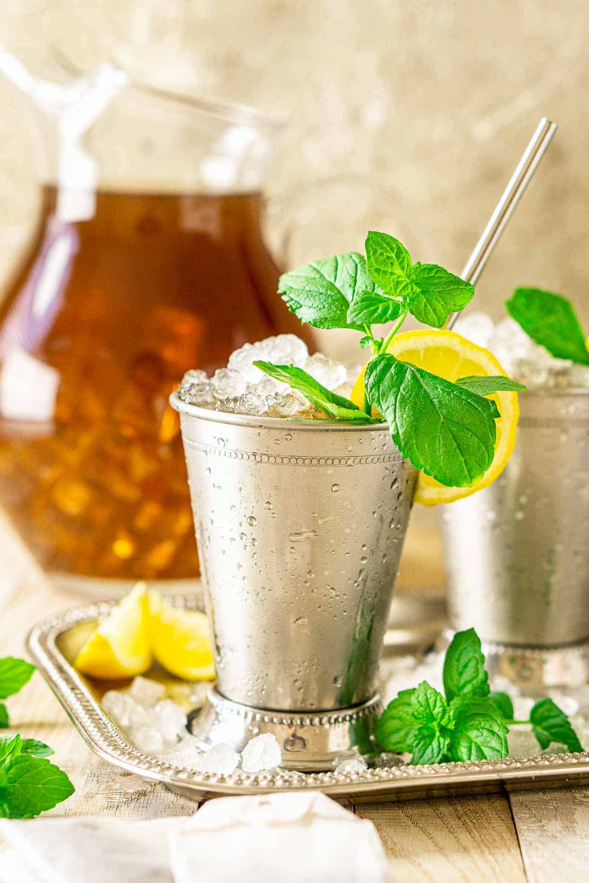 A close-up shot of a sweet tea mint julep on a silver platter with mint sprigs around it.