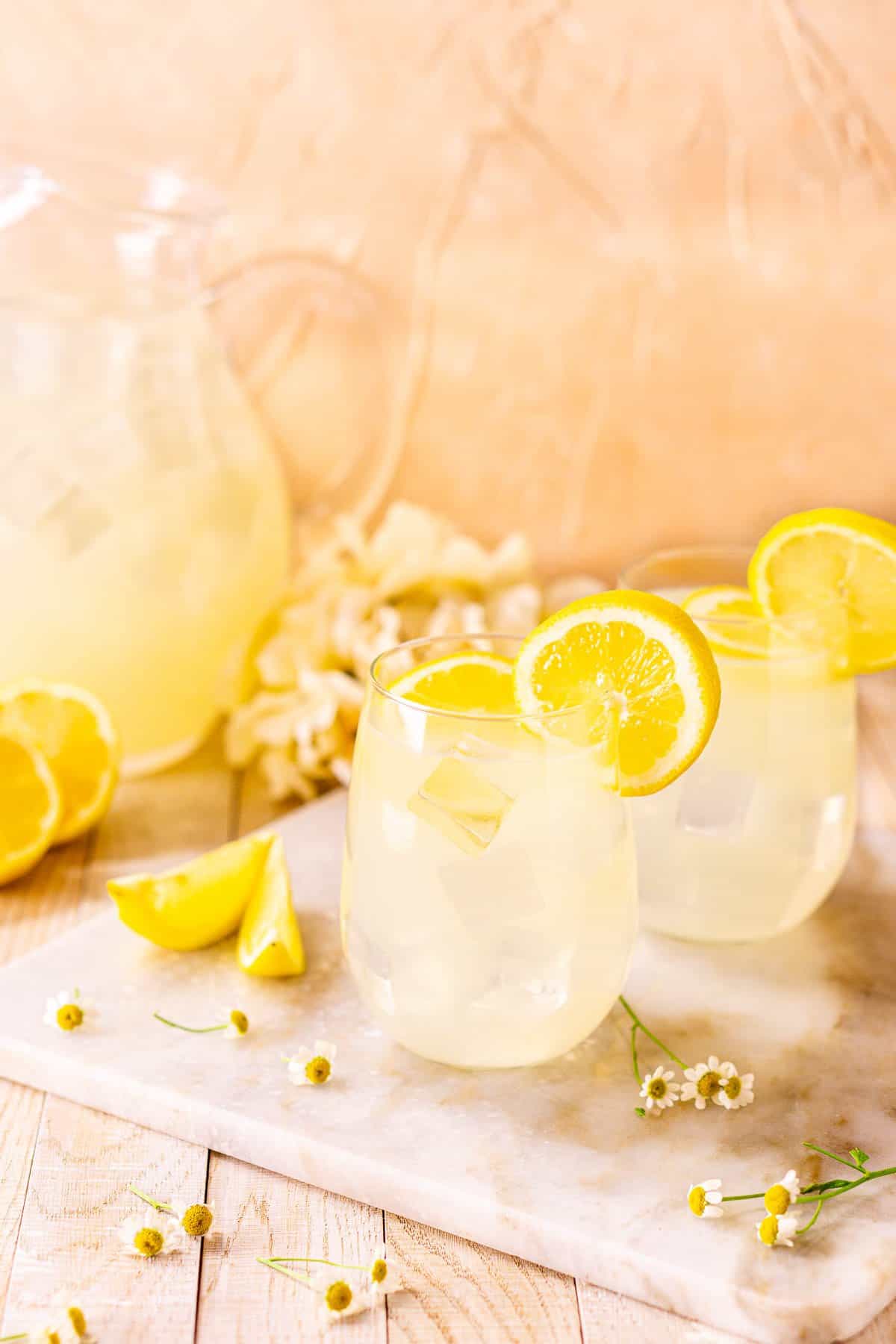 Two tequila lemonade cocktails on a white marble platter from an upward angle.