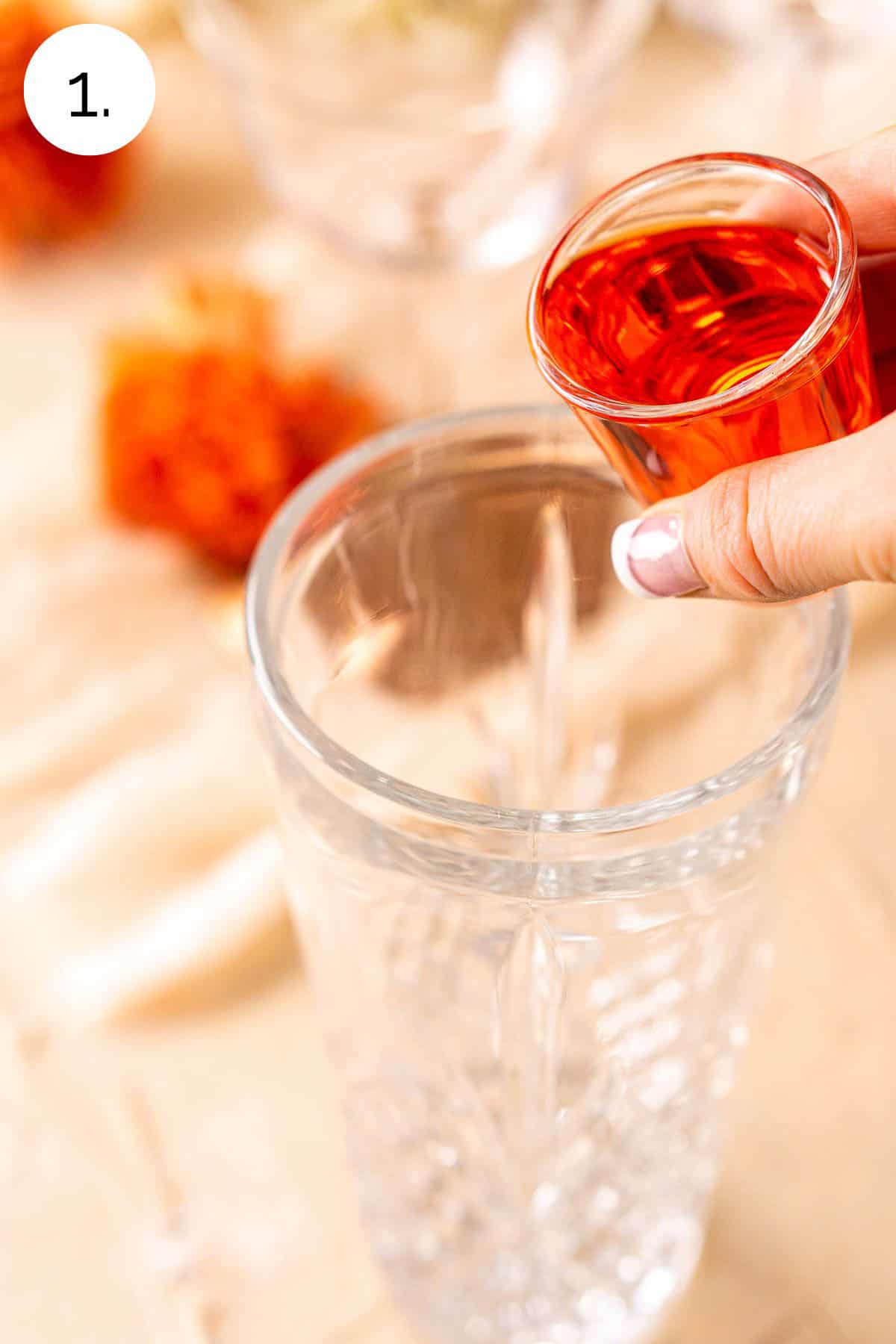 Pouring the Aperol in a clear cocktail shaker before adding the other ingredients.