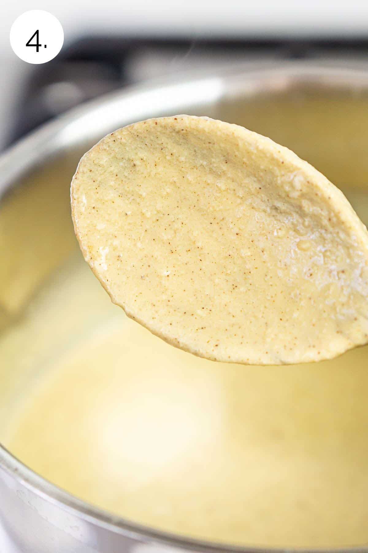 The ice cream custard mixture coating a wooden spoon after cooking on the stove.