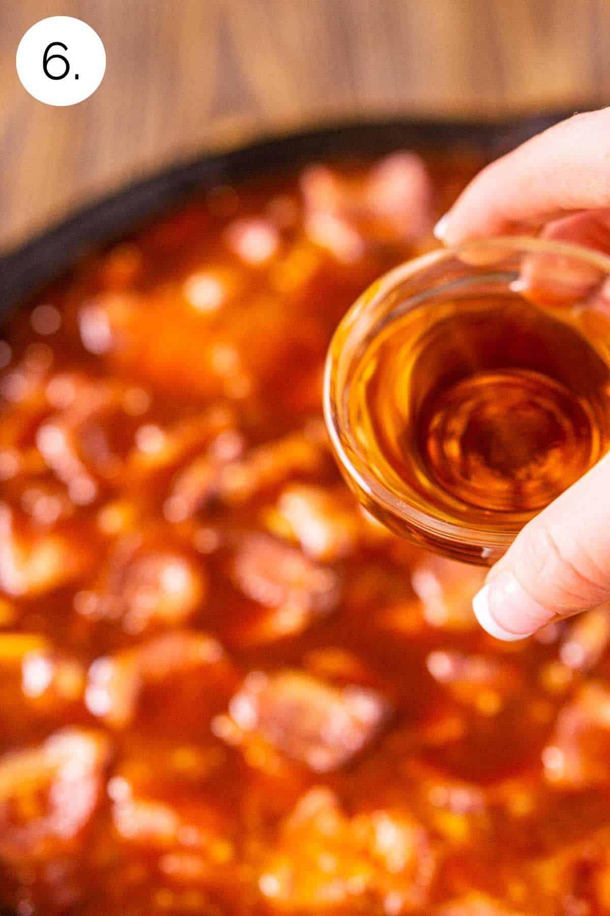 Pouring the bourbon into the baked beans after smoking for three hours.
