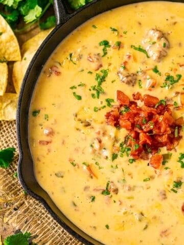 An aerial view of the smoked queso dip on burlap with cilantro and crushed tortilla chips to the left.