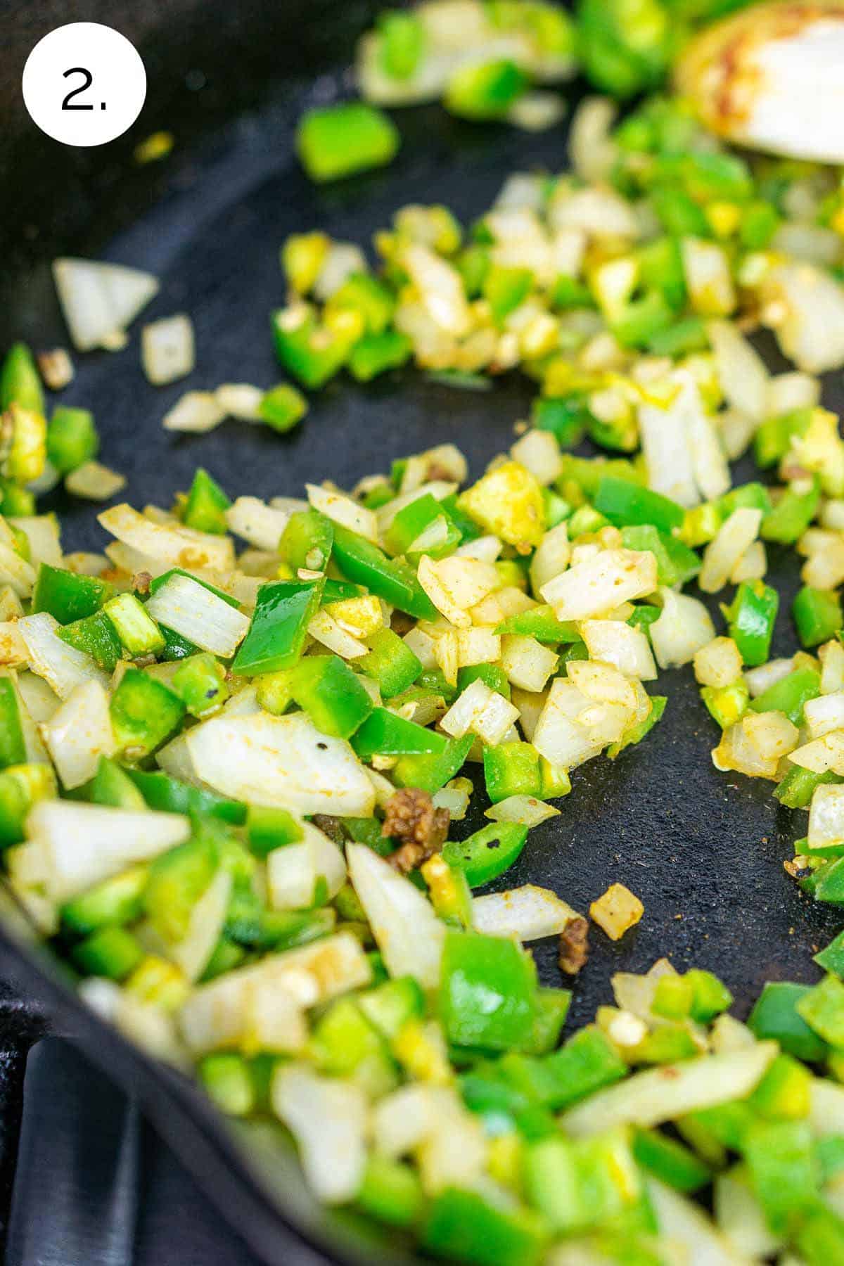 Cooking the onion and jalapeño in a cast-iron skillet on the stove until they soften.